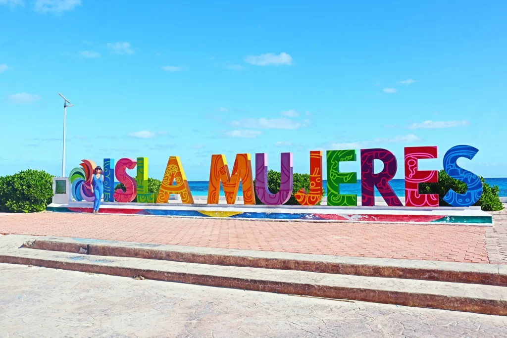 Transporte privado desde el aeropuerto de Cancún a Isla Mujeres 2 Un cartel grande y colorido de «Isla Mujeres» con vistas al mar